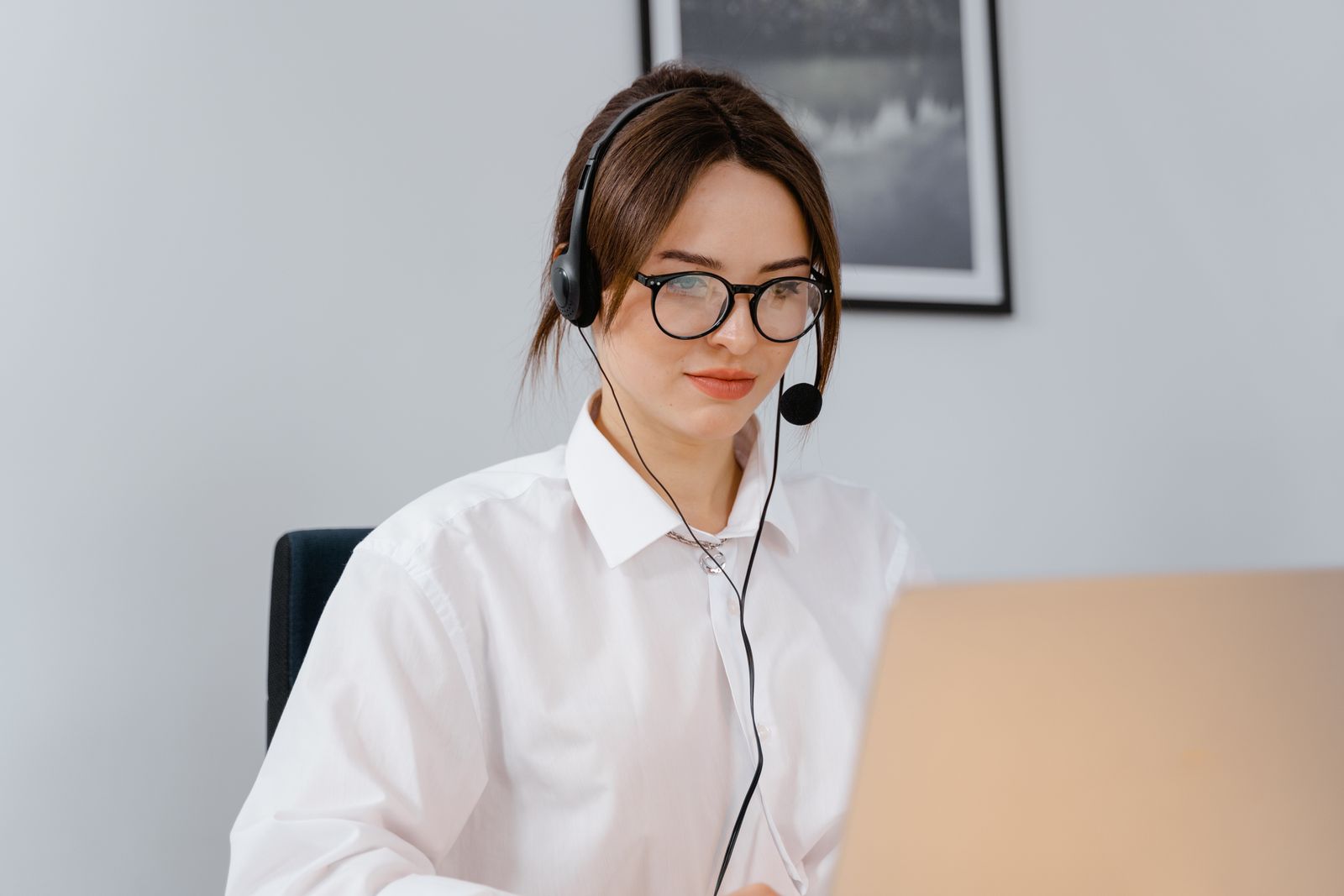 En kundservicemedarbetare med headset vid en bärbar dator